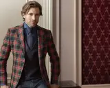 Man in a festive tartan blazer, dark blue shirt, tie, and vest. This is what holiday attire looks like.