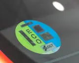 Mini etiqueta eco en parabrisas. Muestra el distintivo DGT y códigos QR para identificar vehículos de bajas emisiones.