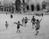 Bambini corrono in una piazza storica, un'immagine piena di movimento e gioia, perfetta come idee per foto.