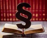 Symbol paragrafu na otwartej księdze, sugerujący karę finansową dla pracownika. W tle rząd czerwonych ksiąg.