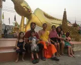 Familia disfrutando de un viaje a Asia con niños, sentados frente a una estatua dorada de Buda reclinado.