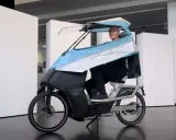 Mann auf einem E-Bike mit Dach, das an ein Auto erinnert.