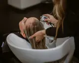 Una parrucchiera sciacqua i capelli di una cliente in un lavatesta, mostrando come lavare i capelli senza shampoo.