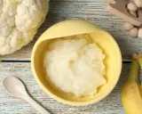 Puré de coliflor listo para servir. Ideas de recetas de coliflor para niños, con plátanos y cuchara.