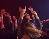 Människor med uppsträckta armar dansar i mörkret, upplysta av rött och blått ljus. En festlig kväll i Stockholm.