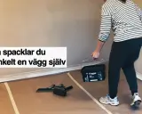 Person med hink med spackel och verktyg för att slipa och jämna ut en vägg.