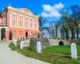 Pałac w Kurozwękach, z flagami narodowymi przed wejściem, zaprasza do odkrywania jego atrakcji.