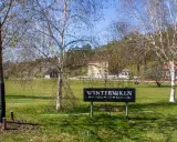Vinterviken Stockholm, en grönskande park med träd och byggnader. En skylt visar "Winterviken - Festvåning - Café - Konferens".