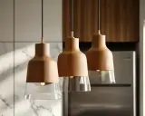 Trzy wiszące lampy z drewnianymi kloszami i szklanymi elementami. Idealne, by rozjaśnić kuchnię, zastanawiasz się, ile lumenów do kuchni potrzebujesz?