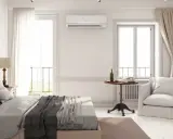 Un dormitorio luminoso con cama, armario de madera y aire acondicionado. La unidad de aire acondicionado está colocada estratégicamente en la pared, mostrando dónde colocar el aire acondicionado en un dormitorio para una climatización óptima.