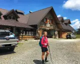 Ragazza con zaino e bastoncini da trekking davanti alla malga Lavareit, con un pick-up e un'auto parcheggiati.
