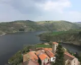 Villaggio pittoresco con tetti rossi e campanile affacciato su un lago serpeggiante, incastonato tra colline verdi vicino a Roanne, Francia.