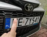 Palec wskazujący na tablicy rejestracyjnej samochodu. Czy to zgubiona rejestracja?