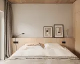 Acogedor dormitorio sin cabecero, con cama de lino, arte abstracto y armario de madera.