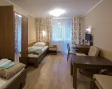 Pokój w sanatorium Włókniarz Busko-Zdrój: dwa łóżka, szafa, biurko z komputerem i stolik.