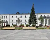 Sanatorium Świt w Solcu-Zdroju, biały budynek z balkonami i łukami, otoczony zielenią i kwiatami.