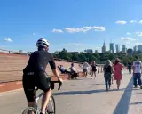 Rowerzysta na moście w Warszawie, w tle panorama miasta. Idealne miejsce na odkrywanie tras rowerowych Warszawa i okolice.