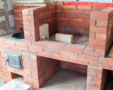 Construcción de diversos tipos de chimeneas de obra, con ladrillos rojos y detalles metálicos.