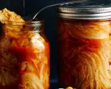 Zwei Gläser mit fermentiertem Chinakohl, bereit für das authentische kimchi rezept original. Ein Löffel ragt aus dem linken Glas.
