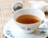 Aromaticzna herbata Earl Grey, znana ze swoich właściwości pobudzających i relaksujących, w eleganckiej filiżance z niebieskimi kwiatami.