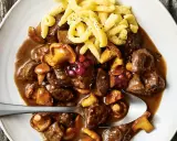 Herzhaftes Rehgulasch mit Rotwein, Pilzen und Preiselbeeren, serviert mit Spätzle. Ein köstliches Rehgulasch Rezept.