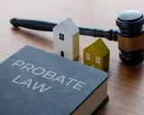 Księga "Probate Law", młotek sędziowski i dwa domki symbolizują dziedziczenie. Dowiedz się, ile procent zachowek przysługuje.