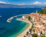 Malownicze miasteczko na wyspie Brač z portem pełnym łodzi, plażą i kamiennymi domami pod czerwonymi dachami.