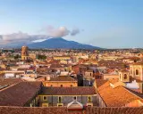 Vista panoramica di Catania con l'Etna sullo sfondo. Tetti rossi, cupole e palazzi storici offrono spunti per le cose da fare a Catania.