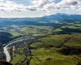 Widok na dolinę z rzeką i miasteczkiem, w oddali majaczą góry Tatry, które przypominają trzy korony. Wysokość widoku zapiera dech.