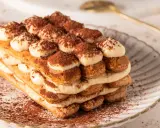 Pyszne tiramisu bez jajek, warstwowo ułożone biszkopty i krem, posypane kakao. Idealne na deser.