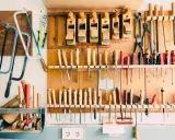 Un bel aménagement atelier avec des rabots, des scies, des tournevis et d'autres outils de menuiserie bien rangés sur un panneau en bois.