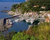 Maratea: un incantevole porto con barche ormeggiate, case colorate e vegetazione lussureggiante. Scopri cosa vedere nel suo centro storico.