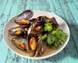 Un plat de moules au roquefort, garni de persil frais, baignant dans une sauce crémeuse.