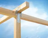 Stabile Holzverbindungen mit Metallwinkeln sichern die Balkenkonstruktion gegen den blauen Himmel.