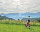 Ciclista con bici da enduro ammira il panorama montano. Un'avventura in bici, forse a Cervia, tra prati fioriti e cime nebbiose.