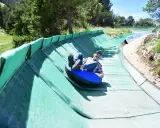 Un homme souriant dévale une piste verte en luge gonflable, profitant des activités Mont Ventoux.
