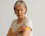 Donna anziana con cerotto giallo sul braccio, preoccupata per i possibili effetti collaterali del vaccino antinfluenzale.