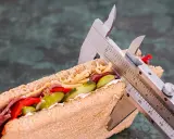 Kanapka z serem, mięsem i warzywami, mierzona suwmiarką. Wygląda na to, że ma duzo kcal.