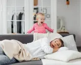 Niña emocionada sobre el sofá, mientras su madre se asusta. ¡Un día típico con el horario para niños en casa!