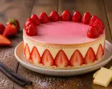 Gâteau rond avec un glaçage miroir fraise, décoré de fraises fraîches et de tranches de fraises sur le pourtour.