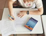 Uczeń pisze wypracowanie, a obok leży słownik "Oxford Essential Dictionary". Zastanawia się, co to jest "suffix" i jak go użyć.
