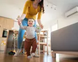 Mamma aiuta il suo bambino a fare i primi passi, con l'aria condizionata neonati che garantisce un clima ideale in casa.