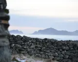 Kamienna ściana z szarego bazaltu na tle morza i gór.