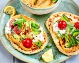 Leckere kalte gerichte ohne kochen: Fladenbrot mit Hummus, Avocado, Tomaten, Gurke und Frischkäse. Garniert mit Kräutern und Zitrone.