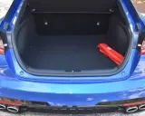 Maletero abierto de un Kia Stinger azul, con un botiquín rojo en el interior.