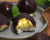Chokladöverdragna biskvier med gul kräm och en bit av en mintkvist. Perfekt för att frysa in och njuta av senare.