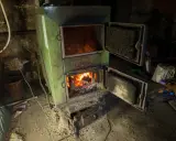 Zielony piec z otwartymi drzwiczkami, w którym pali się ogień. Pytanie o kotły klasy 1 do kiedy jest ważne dla ogrzewania domu.