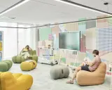 Un espace de repos coloré avec des poufs confortables et un mur à motifs géométriques. Deux personnes lisent tranquillement.
