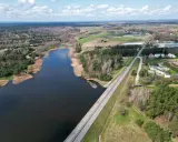 Widok z lotu ptaka na zalew domaniowski, otoczony lasami i polami. W oddali widać zabudowania.