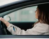 Kobieta za kierownicą, zastanawia się, od ilu lat można mieć prawo jazdy AM.